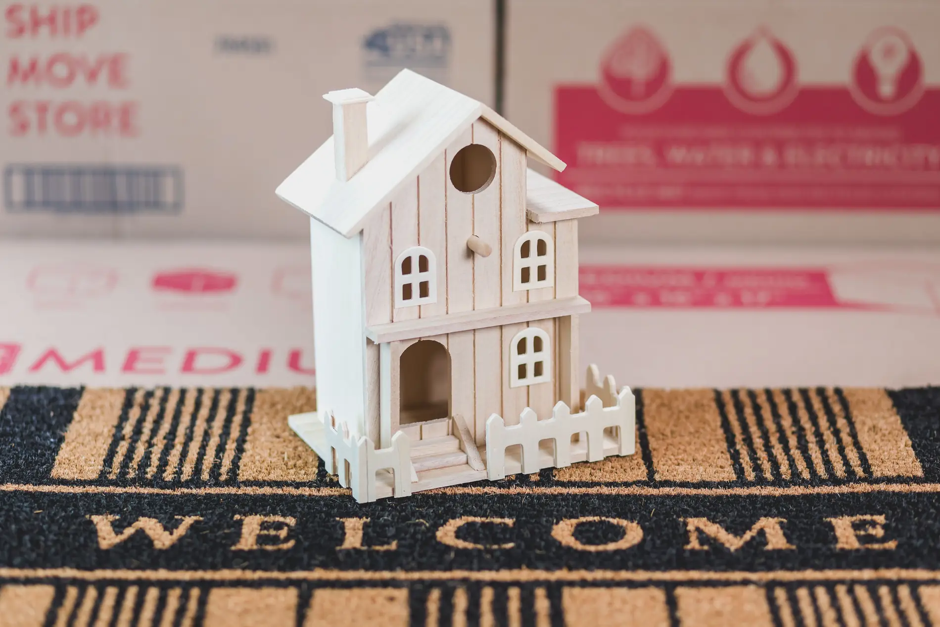 A small house model placed on a doormat, symbolising a move to a new home