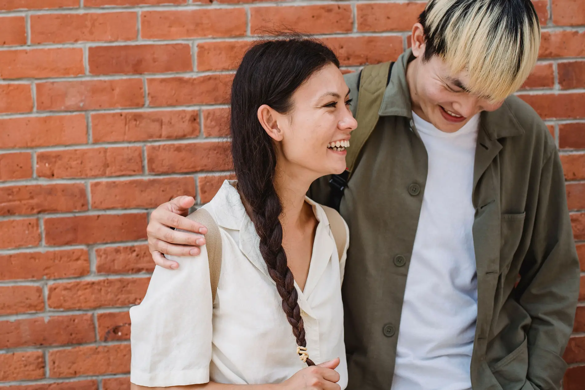A smiling couple standing together against a brick wall
