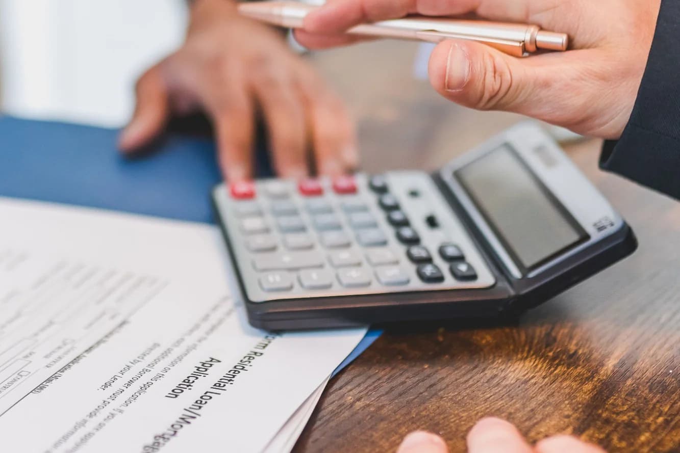 A calculator and pen resting on a residential loan application form