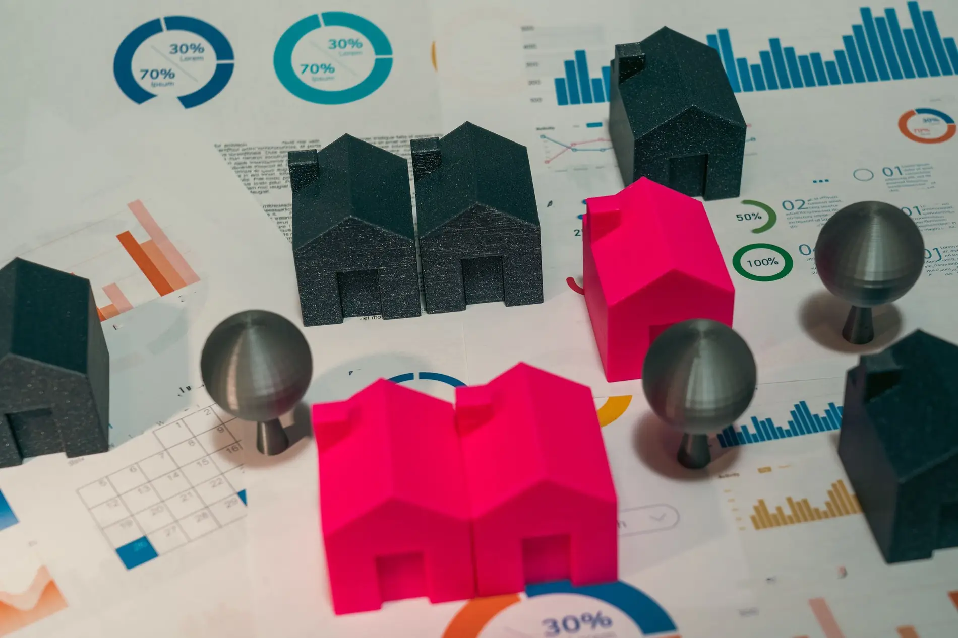 Miniature house models of different colours arranged on printed charts and calendars