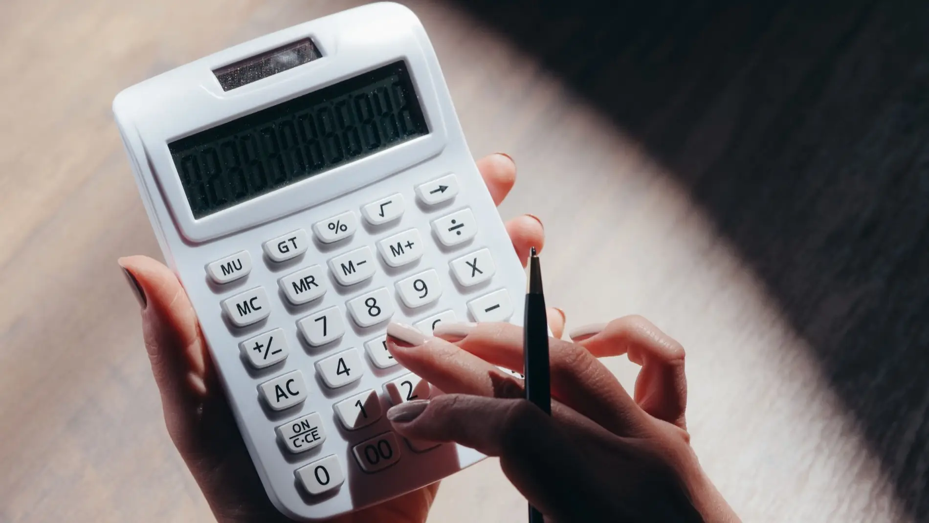 Hands holding a calculator and pen while working out property figures