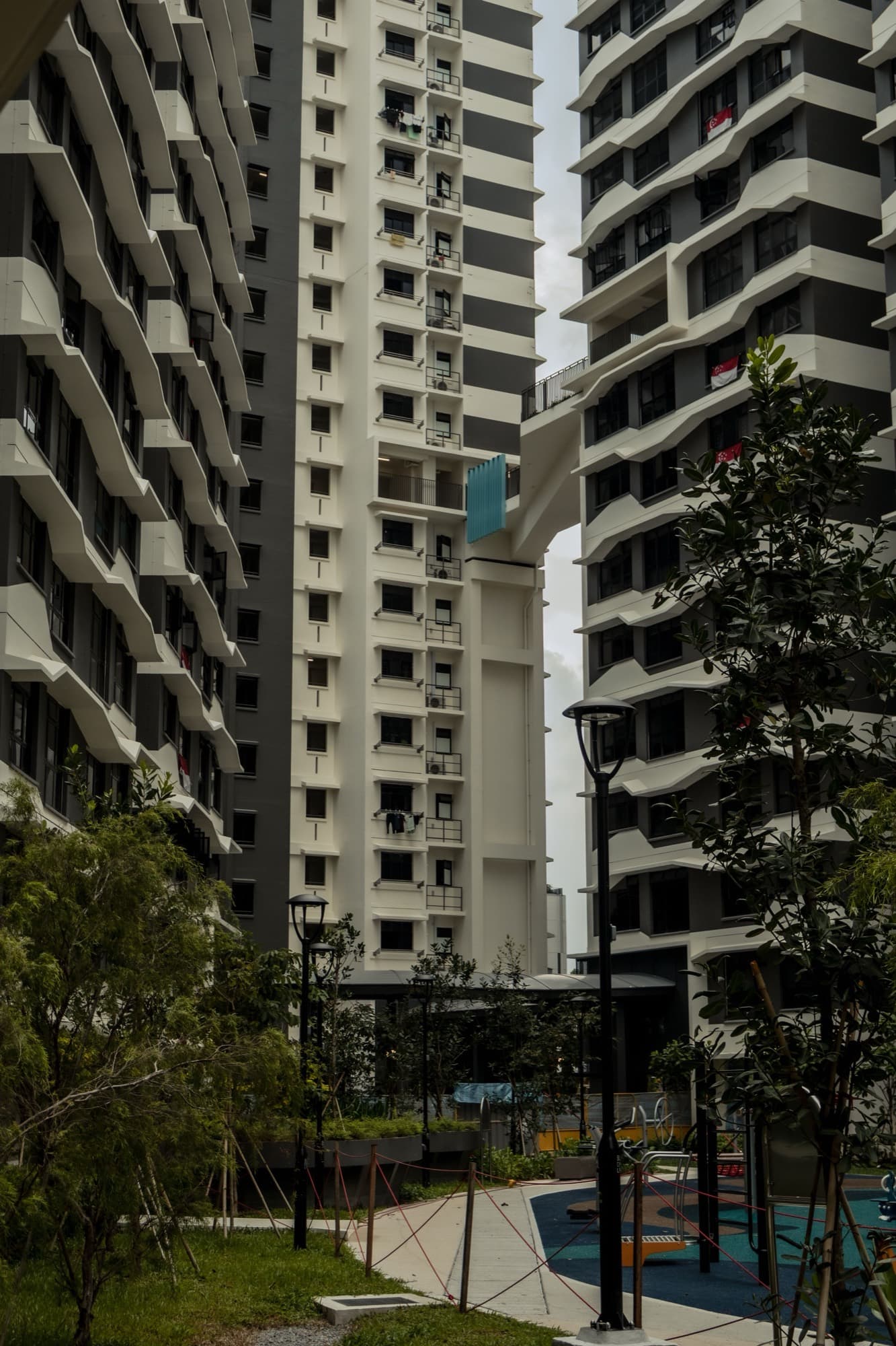Newer HDB towers in Singapore connected by a sky bridge, with a playground below