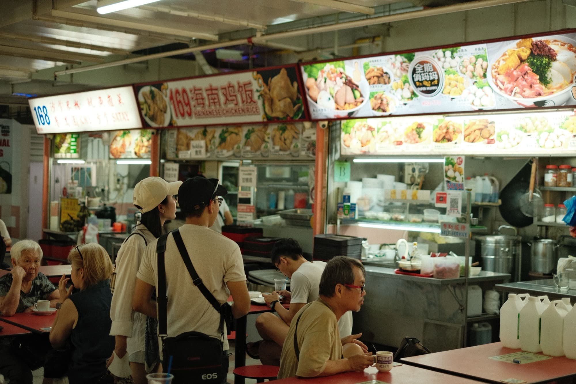 Multiple generations of a Singapore family at a hawker centre, from elderly patrons to young adults
