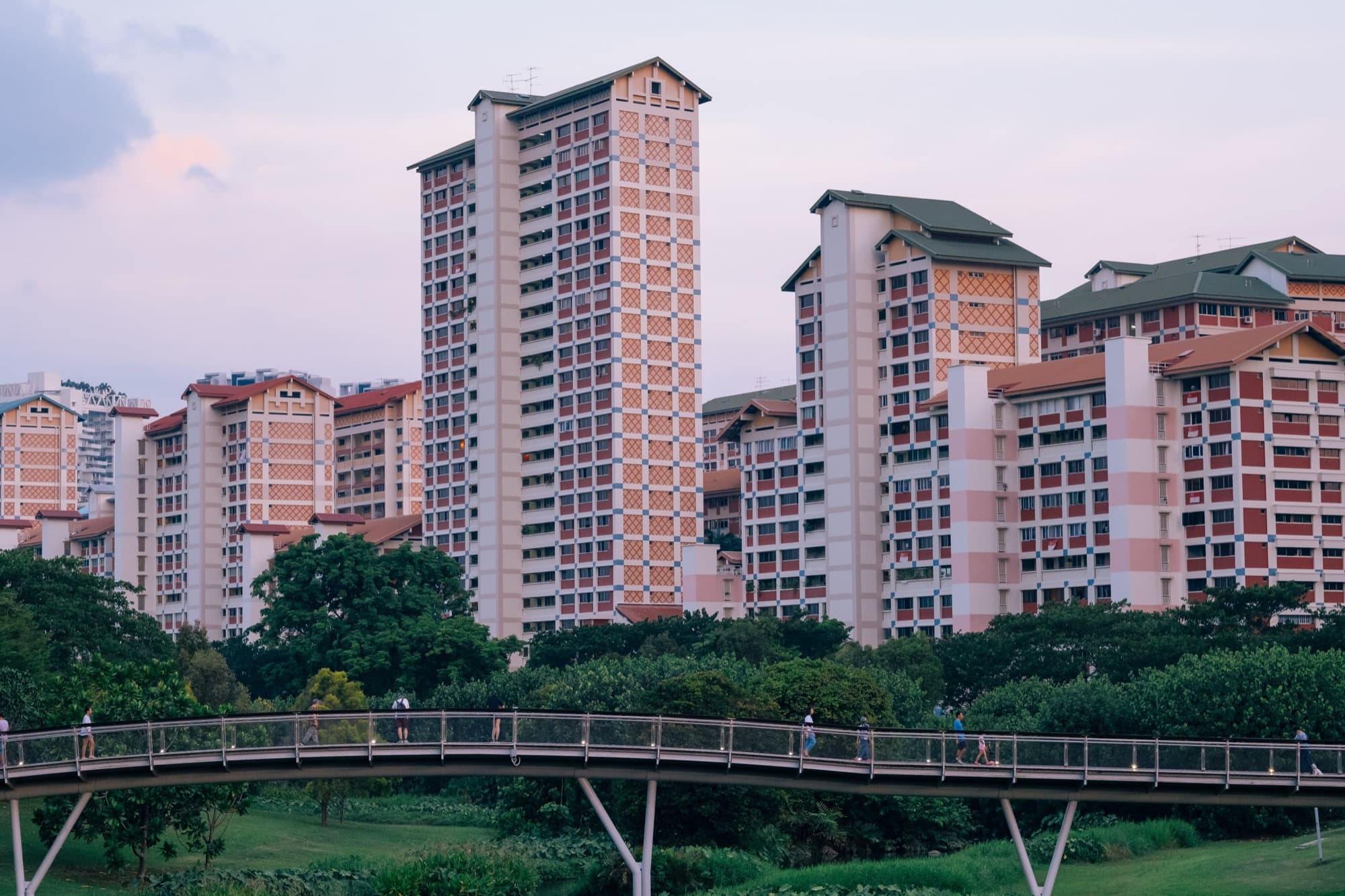 Colourful Singapore HDB blocks beside a park footbridge at dusk
