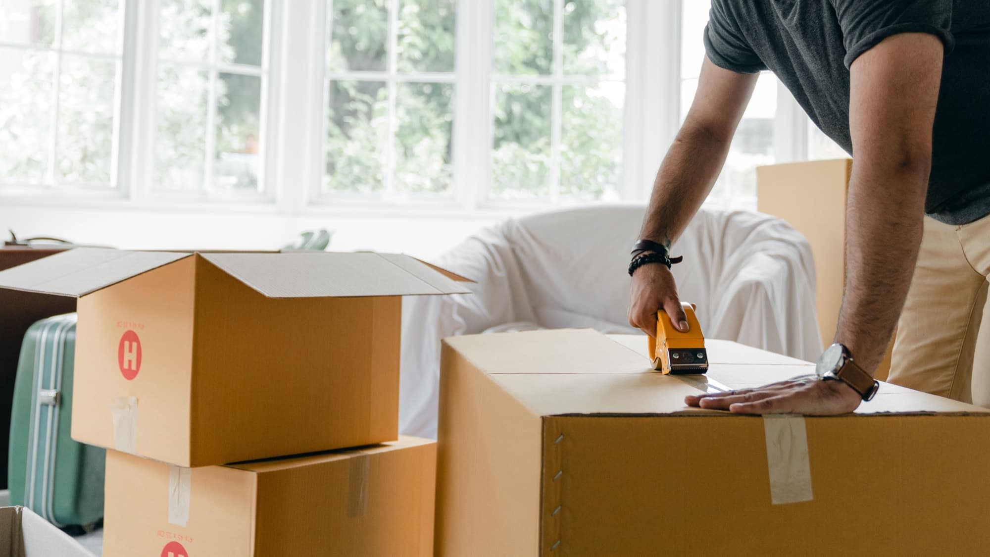 A homeowner taping up moving boxes while packing for a house move