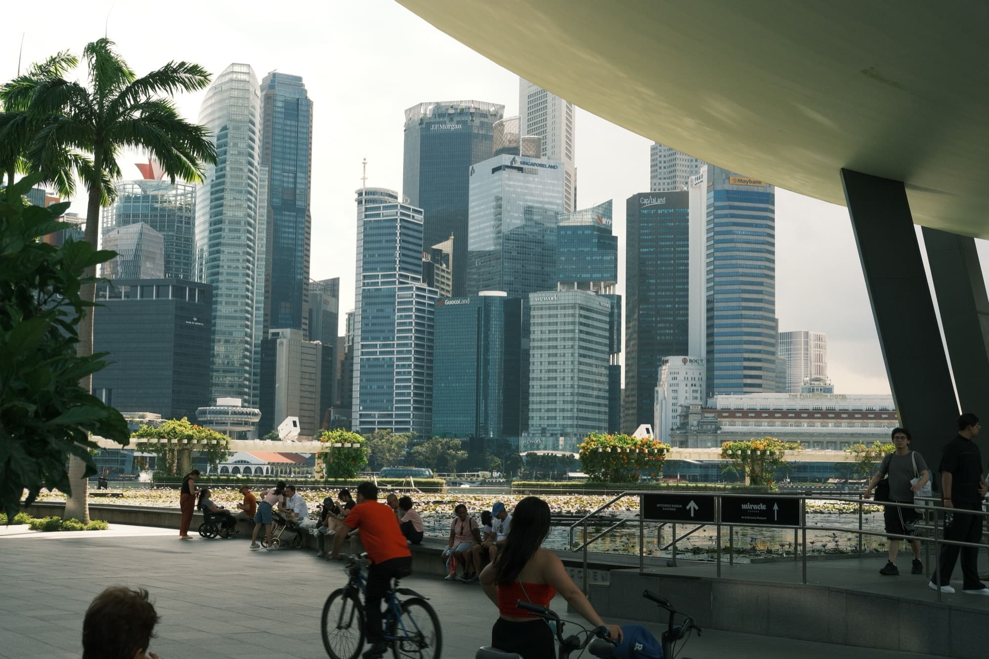 People walking together across a bridge with the Singapore skyline behind them