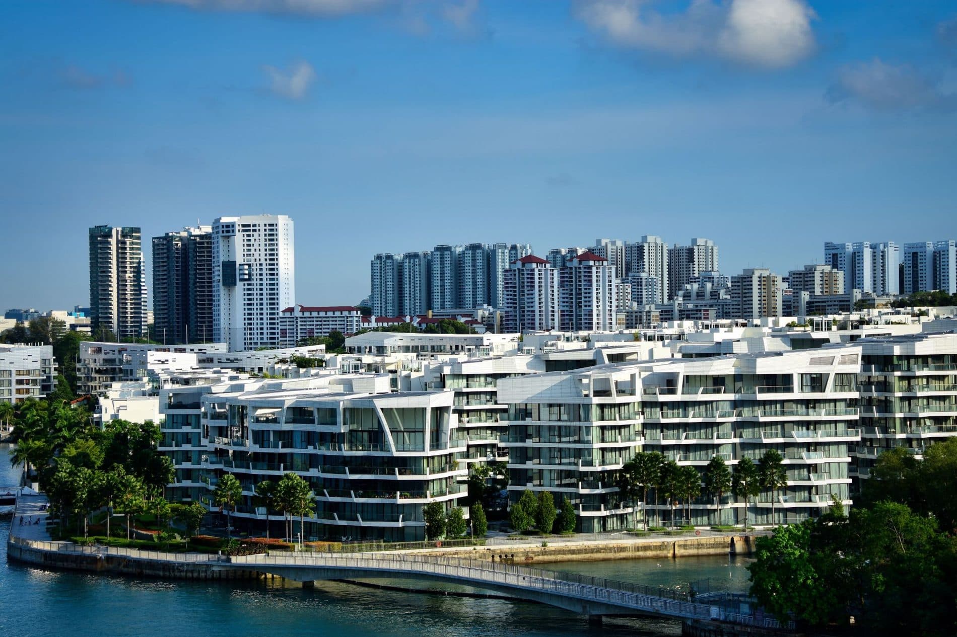 Modern waterfront condominium blocks beside a river, with HDB towers in the background
